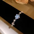 Detailed macro view of a silver bracelet featuring a blue cat's eye clover and zircons. - Blue