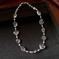 Detail view of transparent geometric crystal beads on a minimalist silver chain necklace - White