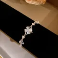 Close-up of elegant cat-eye stone four-leaf clover bracelet with sparkling zircons - White