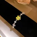 Macro view of silver bracelet featuring a glowing yellow cat's eye four-leaf clover - Yellow