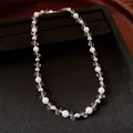Close-up detail of pearl and crystal flower beaded necklace on elegant black display - White Base Gold Frame Pearl