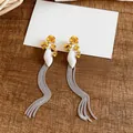 Close-up detail of silver tassel earrings with yellow flowers and white petals decoration - Yellow-White