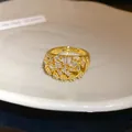 Close-up of 18k gold plated ring with geometric hollow pattern and sparkling zircons. - Gold