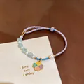 Close-up detail of hand-woven braided rope bracelet with elegant pearls and clover pendant. - Pink Blessing Clover Style