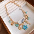 Détail du collier doré orné de breloques en émail bleu sarcelle (coquillages et fleurs) - Or-Bleu