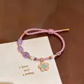 Detailed view of hand-woven pink cord bracelet with flower pendant and purple beads - Purple Cherry Blossom Style