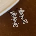 Detailansicht der eleganten, hohlen Dreifach-Blumenohrringe aus Silber auf braunem Samt. - Hohler Dreifach-Blumenstil (HE34049) / Silber