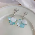 Détail de boucles d'oreilles étoile de mer avec glands en coquille et pétales bleus - Bleu