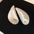 Detailed macro view of silver-tone teardrop earrings with a textured polished surface - Silver