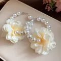 Gros plan détaillé de boucles d'oreilles créoles vintage avec perles et fleurs en tissu - Blanc