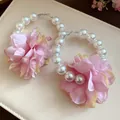 Détail rapproché d'élégantes boucles d'oreilles créoles fleurs en tissu rose et perles. - Rose