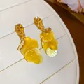 Detailed view of yellow shell tassel earrings with gold-toned metal accents for vacation. - Yellow