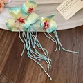 Close-up of handmade fabric flower hair clips with blue beaded tassels. - Duckbill Hair Clips / Green