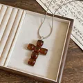 Close-up detail of amber resin cross pendant on a silver snake chain. - Necklace-Silver-Coffee