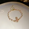 Vue détaillée du bracelet de perles élégant avec un pendentif papillon en cristal rose. - Bracelet (Or)