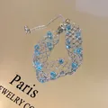 Close-up of silver-tone lace bracelet with sparkling blue beads on golden surface. - Summer Lace Style