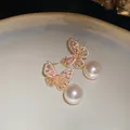 Détail rapproché de boucles d'oreilles papillon élégantes avec cristaux roses et perles blanches - Boucles d'Oreilles (Or - Tige Argentée)