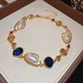 Luxurious close-up of a gold geometric necklace with pearls and colored gemstones. - Necklace / Gold/Blue/White