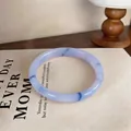 Detailed macro view of a lavender chalcedony bangle placed on a stylish vintage book - Style 19