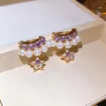 Primo piano dettagliato di eleganti orecchini pendenti a forma di stella con perle e zirconi. - Oro-Viola-Bianco