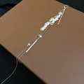 Eleganter langer Quastenohrring mit klaren Steinen und Silberstäben auf braunem Lederhintergrund - Einzelner Stil / Weiß