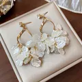 Detailed macro view of zircon stud and pearlescent shell petal tassels on golden earrings - Gold