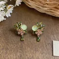 Detailed macro view of elegant green zircon flower earrings with teardrop pendants - Gold-Green