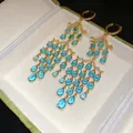 Detailaufnahme der luxuriösen langen Quastenohrringe mit blauen runden und Tropfensteinen - Lange Quaste / Gold-Blau