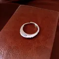 Close-up of a minimalist silver open ring featuring a sparkling zircon on leather - Silver