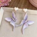 Détail montrant les ailes de papillon en résine violette et les clous de cœur de ces boucles - Clou Cœur Papillon Dégradé / Tige en argent 925 / Violet et Blanc