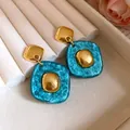 Primo piano di orecchini vintage in resina glitterata verde acqua con dettagli dorati - Blu
