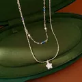 Detail view of a double-layered silver necklace with blue beads and a star pendant. - Glass Style / Silver-Blue
