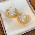 Macro shot of elegant gold-plated C-shaped hoop earrings with pearls and zircon stones - C-Shape Stud Earrings / Gold