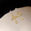 Close-up of 18k gold plated cross earrings with sparkly cubic zirconia stones. - Earrings / Gold