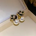 Detailed macro view of 14k gold plated zircon flower earrings with white pearls. - Silver Post-Black-White (Gold Plated)