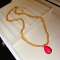 Elegante collana vintage di perline con ciondolo a goccia rosso in un portagioie raffinato. - Collana / Ambra Caffè con Goccia Rossa
