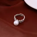 Close-up detail of a vintage silver lace pearl ring on elegant dark red velvet background - White Pearl Style / Silver