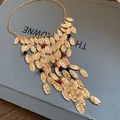 Close-up detail of vintage gold pleated oval fringe necklace with red and black beads. - Necklace / Gold