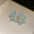 Nahaufnahme von hellblauen Emaille-Blumenohrringen mit Zirkonia und Perlen. - Silber-Ohrstecker-Stil / Silber-Blau