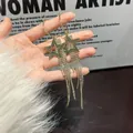 Primer plano de pendientes de estrella dorados con borlas de pedrería muy brillantes. - Estilo Estrella de Borla / Plateado