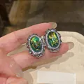 Close-up view of vintage oval stud earrings with green resin and pavé rhinestones. - Vintage Oval Style / Green
