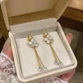 Detailed view of elegant gold floral clip-on earrings with long tassels in a gift box. - White Flower Tassel Ear Clips (HE32924) / 1 Pair Pack / Gold