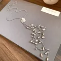 Vue détaillée d'un collier à pompon argenté avec des pendentifs goutte et cœur. - Argent