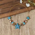 Detailed view of the ocean-themed starfish and pearl necklace on a rustic backdrop - Necklace - Gold / Blue
