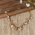 Detailed view of a gold starfish and seashell pearl necklace on a beach-themed background. - Necklace - Gold / Gold