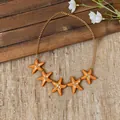 Close-up view of five orange enamel starfish pendants on a golden chain necklace. - Waist Chain-Gold / Orange