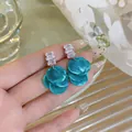 Close-up view of geometric zircon earrings with layered teal shell discs in a resort style - Blue
