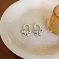 Elegant French bow stud earrings featuring sparkling zircon stones and delicate white pearls - Silver
