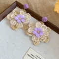 Detailed view of Bohemian raffia flower earrings with purple fabric accents - Steel Pin Style / 1 Pair Pack / Purple