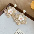 Close-up of woven raffia flower earrings with delicate fabric petals and gold center. - Steel Pin Style / 1 Pair Pack / White-Pink